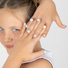 A close-up of a child's hands with light blue and white cloud-patterned nail art, with part of the child's face visible against a plain light gray background.