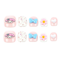Ten decorative nail tips arranged in two rows of five on a plain white background. The set includes pink rounded-square tips with cartoon character designs, white speckled tips, light blue bow tips, a pink-and-white flower tip with a yellow center, and a pale pink heart tip with a white heart center.