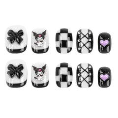 A set of ten black and white decorative press-on nails arranged in two rows of five on a plain white background. The designs include glossy black bows, a Kuromi cartoon character, checkerboard patterns, silver rhinestone accents, and a small purple heart.