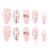 A set of 10 pink press-on nails arranged in two rows of five on a plain white background. The designs include glossy pink nails with bows, glittery pink nails with hearts, a pink-and-white cartoon character (My Melody) nail, silver rhinestone accents, and a white nail with a pink heart.