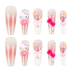 Ten false press-on nails arranged in two rows of five on a plain white background. The set includes glittery nude-pink nails, a Hello Kitty design with a pink bow, floral nail art with bows and flowers, and pink bow embellishments.