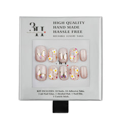 A 10-piece reusable press-on nail kit by 3H Handcrafted Love, displayed in its original light gray packaging box. The nails feature a shimmering nude-pink base with various designs including white daisies with yellow centers, metallic gold butterflies, and pink shimmery accents.