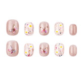 Ten press-on nails arranged in two rows on a plain white background. The set includes glittery nude-pink nails, clear white nails with multicolor confetti, and white nails with yellow dots and butterfly designs.