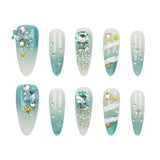 Set of ten artificial press-on nails arranged in two rows of five on a plain white background. The nails feature a light blue to white gradient with various embellishments including rhinestones, pearls, silver beads, and gold star accents.