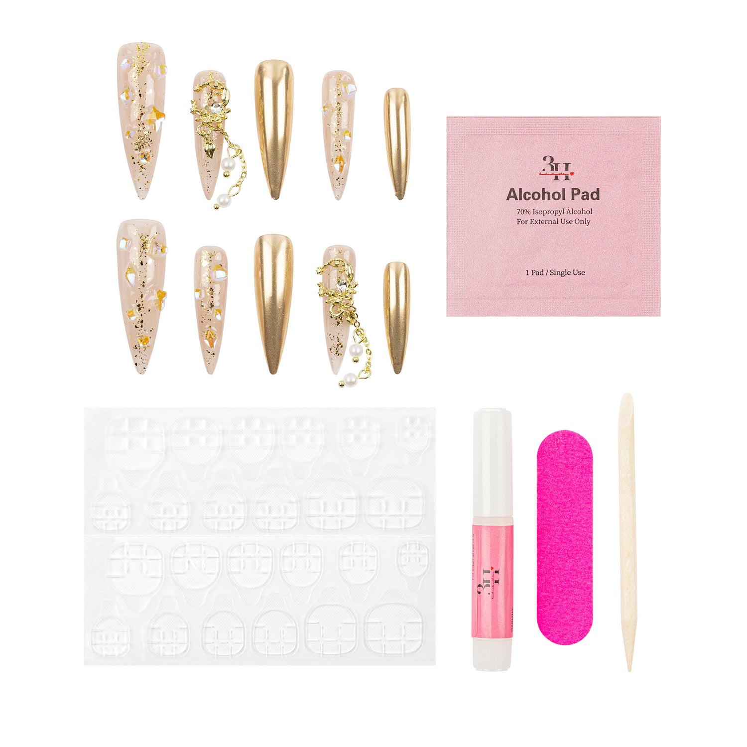 Nail art kit with long coffin-shaped press-on nails in nude and metallic gold with gold foil and chain details, a pink packet of alcohol pad, a white nail stamping plate, a pink nail file, a pink nail polish tube, and a wooden cuticle stick on a white background.