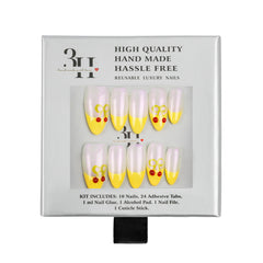 A 10-piece set of reusable luxury press-on nails in a white box. The nails feature a white and yellow split design with small red heart details on the tips.