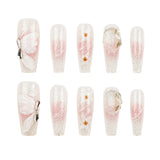 Ten false press-on nails arranged in two rows of five on a plain white background. The nails are clear with fine silver glitter and a soft pink gradient, decorated with white butterfly motifs, small gold flower accents, and metallic ring details.