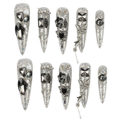 Ten silver glitter stiletto press-on nails with various rhinestone and crystal embellishments, arranged in two rows on a plain white background.