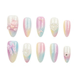 Ten-piece press-on nail set with pastel gradient designs in pink, blue, and yellow, featuring various decorative embellishments like bows, pearls, and a teddy bear on a white background.
