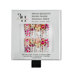 A boxed set of decorative press-on nails in a white retail package. The nails are embellished with pink rhinestones, gold foil, and clear gemstones.