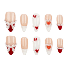 A set of ten false press-on nails arranged in two rows on a plain white background. The nails feature a mix of nude beige, white, red, and pearl embellishments, including heart and bow designs.