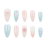 Ten artificial press-on nails arranged in two rows on a plain white background. The nails feature pastel designs including light blue, pale pink, and glossy white, decorated with bows, lace details, flowers, and small green stems.