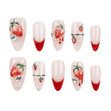 Ten false press-on nails arranged in two rows on a plain white background. The nails have a glossy pale pink base with red gradient tips, some decorated with 3D strawberry designs, rhinestones, and thin black horizontal lines.