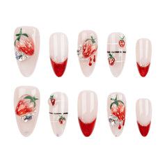 Ten false press-on nails arranged in two rows on a plain white background. The nails have a glossy pale pink base with red gradient tips, some decorated with 3D strawberry designs, rhinestones, and thin black horizontal lines.