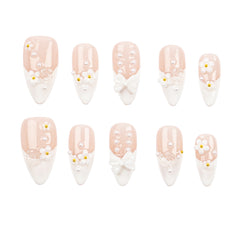 A set of ten almond-shaped press-on nails arranged in two rows on a plain white background. The nails feature a glossy pale blush pink top half and a white French-tip bottom half, decorated with white faux pearls, small white daisy flowers with yellow centers, and one white bow design.