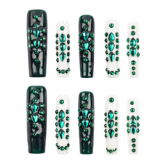 Ten coffin-shaped press-on nails arranged in two rows of five on a plain white background. The nails feature glossy black and white bases decorated with multiple rows of sparkling green rhinestones.