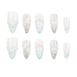 A set of ten false press-on nails arranged in two rows of five on a plain white background. The nails are primarily white with various embellishments including silver glitter, 3D white roses, heart charms, and light blue grid patterns.