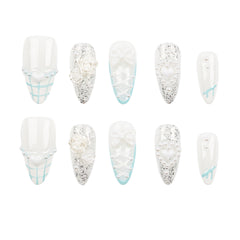 A set of ten false press-on nails arranged in two rows of five on a plain white background. The nails are primarily white with various embellishments including silver glitter, 3D white roses, heart charms, and light blue grid patterns.
