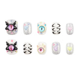 Ten decorative nail charms or bead-like accessories arranged in two rows on a plain white background. The set includes glittery silver pieces with pastel hearts and eyes, black-and-white cat-face designs, and pastel pink, blue, yellow, and lavender eye motifs.