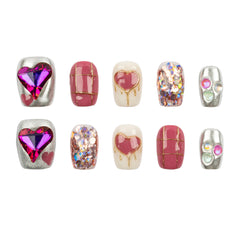 Ten decorative nail art beads or press-on nail tips arranged in two rows on a plain white background. The designs include pink hearts, glittery silver patterns, and metallic silver accents with small pastel gem details.