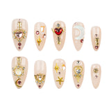 Ten almond-shaped press-on nails with celestial and fantasy designs, including gold key and crown motifs, a red heart, a crescent moon, stars, and rhinestones, arranged in two rows on a white background.