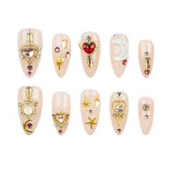 Ten almond-shaped press-on nails with celestial and fantasy designs, including gold key and crown motifs, a red heart, a crescent moon, stars, and rhinestones, arranged in two rows on a white background.