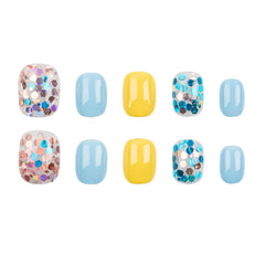 Ten press-on nails arranged in two rows on a white background, featuring light blue, yellow, and glittery multicolor designs.