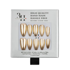 A 10-piece press-on nail kit in its original packaging, featuring metallic gold almond-shaped nails with matching gold adhesive tabs. The packaging is white with black text and a clear window displaying the nails.