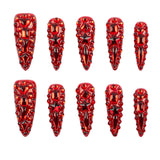 Ten red stiletto-shaped nail art stickers with intricate 3D crystal and bead designs, arranged in two rows of five on a plain white background.