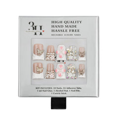 A 3H brand press-on nail kit in its original packaging, featuring 10 decorative nails with pink, white, and gold designs, 24 adhesive tabs, 1 ml of nail glue, an alcohol pad, a nail file, and a cuticle stick.