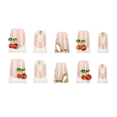 Ten false press-on nails arranged in two rows of five on a plain white background. The nails have a pale pink and white French tip design with some featuring red cherry embellishments with green leaves and gold decorative accents.