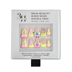 A boxed set of reusable luxury press-on nails. The white retail package shows a clear window with ten decorative nail tips in pastel pink, yellow, green, and nude tones, plus printed text including 'HIGH QUALITY HAND MADE HASSLE FREE' and 'REUSABLE LUXURY NAILS.