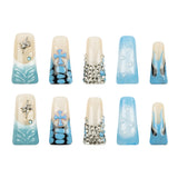 Ten long duck-shaped press-on nails arranged in two rows of five on a plain white background. The nails feature a cream base with light blue gradient designs, silver rhinestone embellishments, and metallic silver cross motifs.
