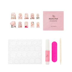Nail art kit with decorative press-on nails, a pink alcohol pad packet, adhesive tabs, a pink nail file, a pink nail glue tube, and a wooden spatula on a white background.