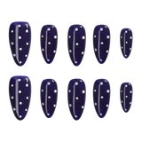 A set of ten dark navy blue press-on nails with white polka dots and white vertical accent lines, arranged in two rows of five on a plain white background.
