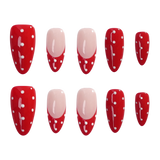 Ten artificial press-on nails arranged in two rows on a plain white background. The nails have a glossy red base with white polka dots and white decorative line details, with two nails featuring a pale pink French tip design.