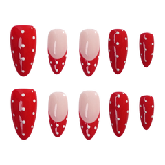 Ten artificial press-on nails arranged in two rows on a plain white background. The nails have a glossy red base with white polka dots and white decorative line details, with two nails featuring a pale pink French tip design.