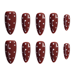 Ten almond-shaped press-on nails with a glossy dark red/burgundy base and white polka dots, arranged in two rows of five on a plain white background.