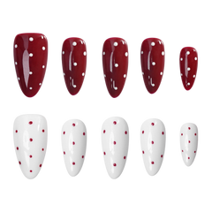 Ten artificial press-on nails arranged in two rows of five on a plain white background. The top row consists of glossy deep red almond-shaped nails with white polka dots, and the bottom row consists of glossy white almond-shaped nails with small red polka dots.