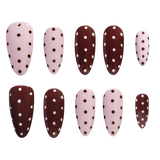 A set of ten false press-on nails arranged in two rows on a plain white background. The nails have an almond shape and are decorated with a polka dot pattern in brown and pink, with alternating light pink and dark brown nails.