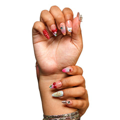 NYC medium almond press-on nails by 3H Nails, featuring mixed nude, red, pink, blue, and silver designs with cherries, polka dots, stars, and rhinestones, shown on hands.