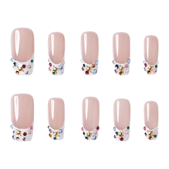 Las Vegas medium square press-on nails by 3H Nails, featuring a nude base with white French tips, multicolor rhinestones, and gold star accents.