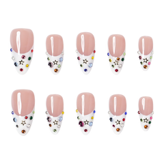Dallas medium almond press-on nails by 3H Nails, featuring a nude base with white French tips, multicolor rhinestones, and gold star accents.