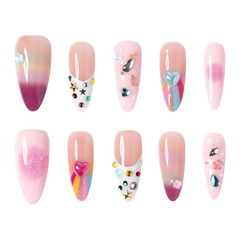 San Francisco medium almond press-on nails by 3H Nails, featuring pastel ombre color with hearts, stars, gems, metallic accents, and colorful French tips.
