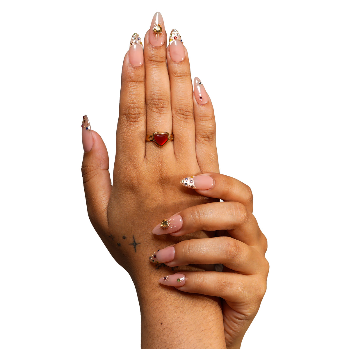 Boston medium almond press-on nails by 3H Nails, featuring a nude base with champagne glitter, multicolor gems, metallic accents, and heart details, shown on hands.
