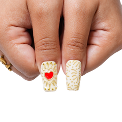 Close-up of Gilded Relic long square press-on nails with ornate gold detailing, pearl-like beads, red and clear gems, and cameo-inspired accents.